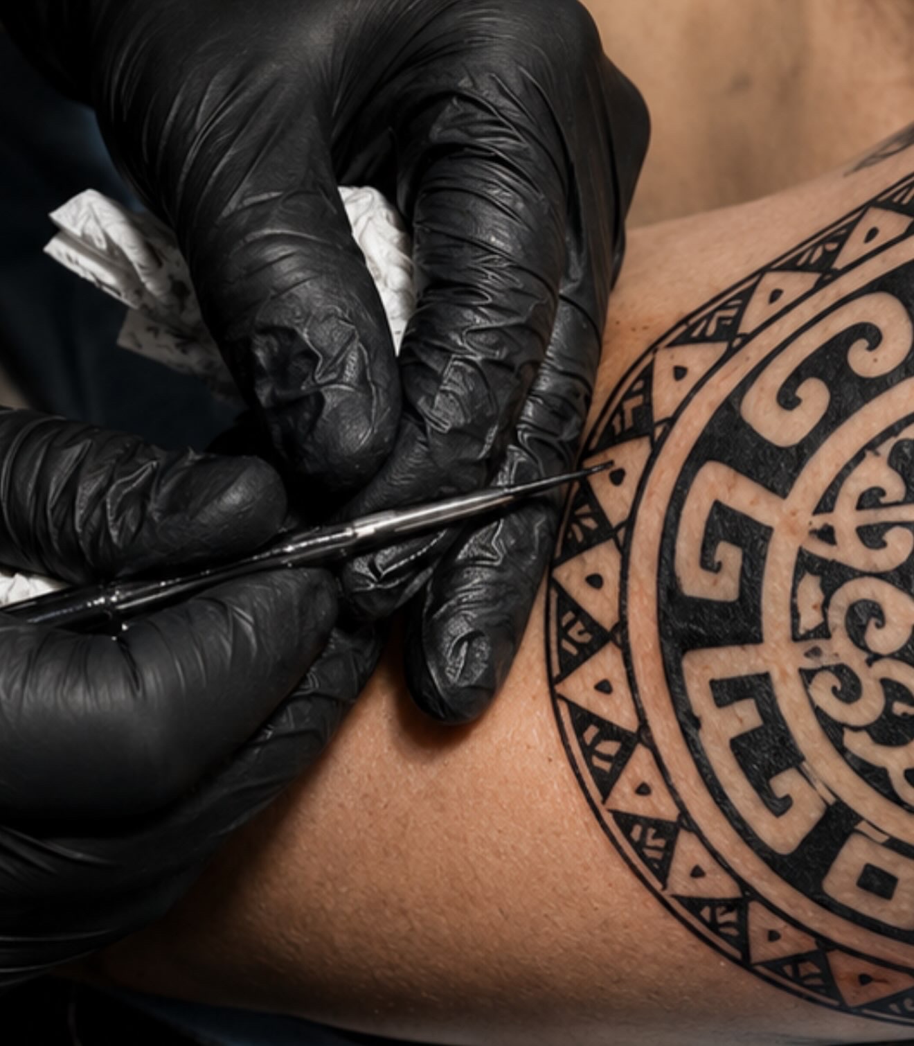 Bamboo tattoo technique at Black Koi Tattoo: an artist works by hand on a patterned tattoo
