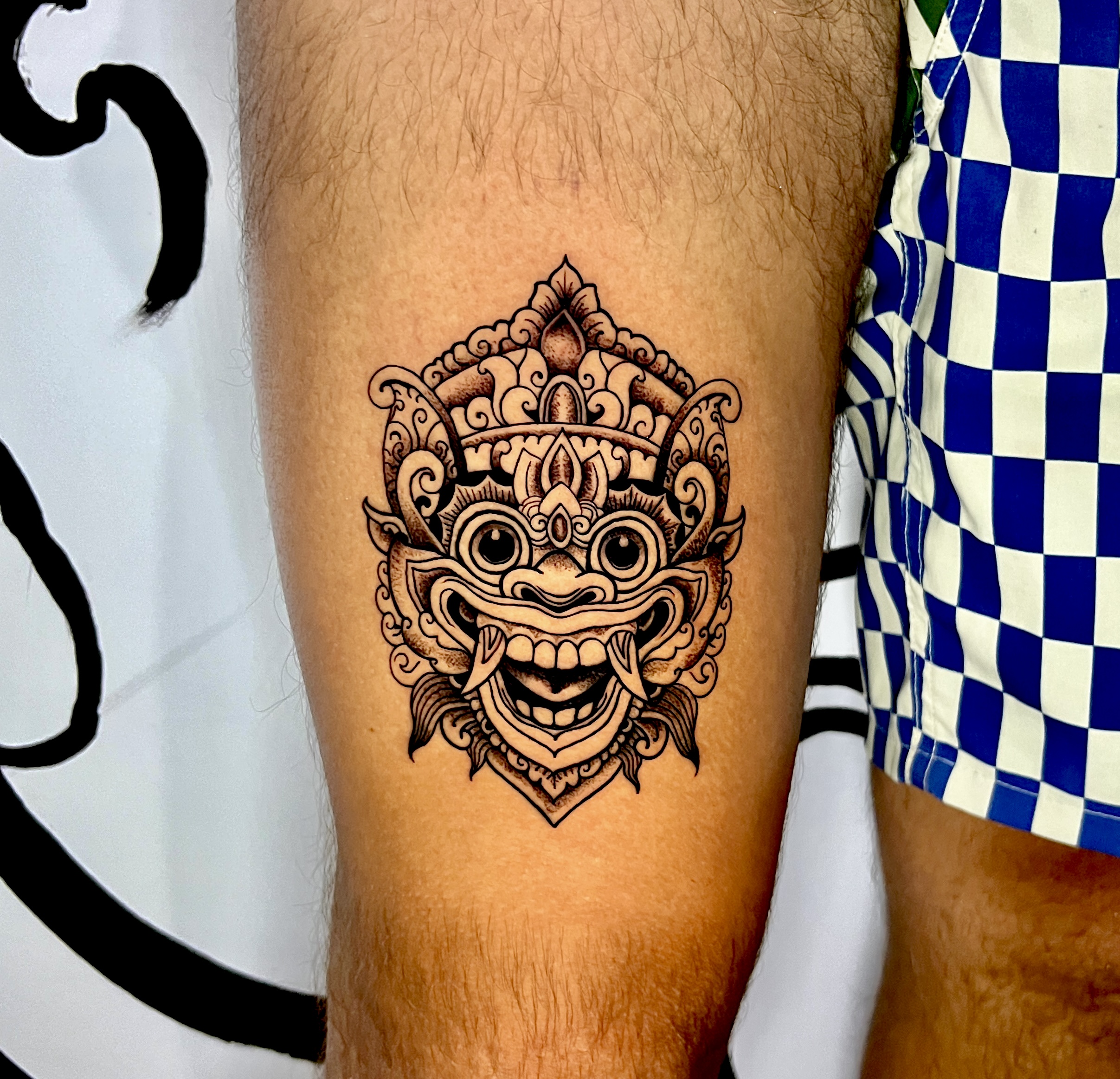 Traditional barong mask tattoo on a thigh
