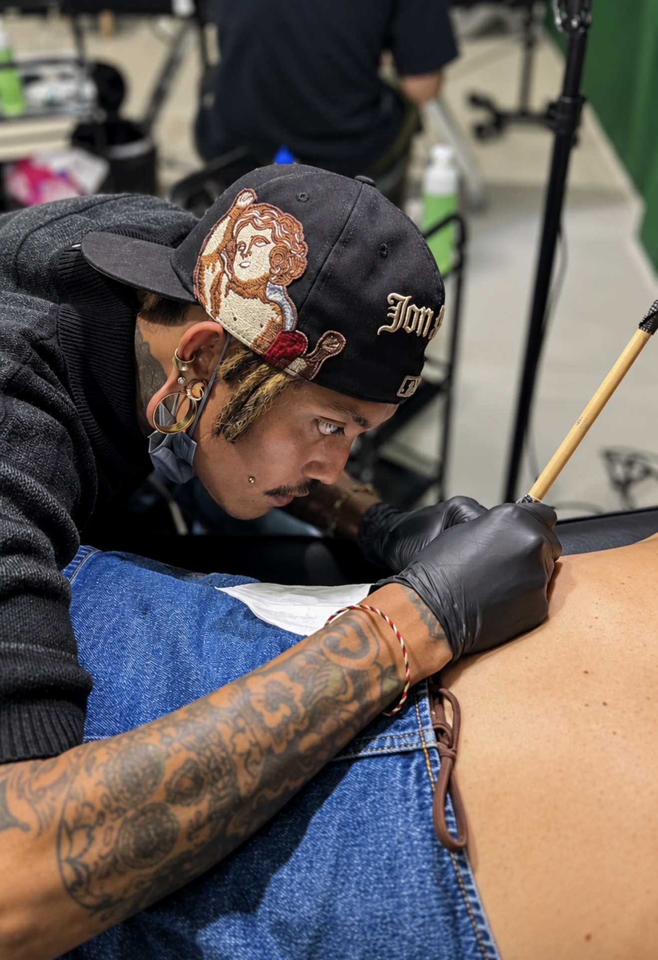 Black Koi Tattoo artist creating a handpoke tattoo with a bamboo rod